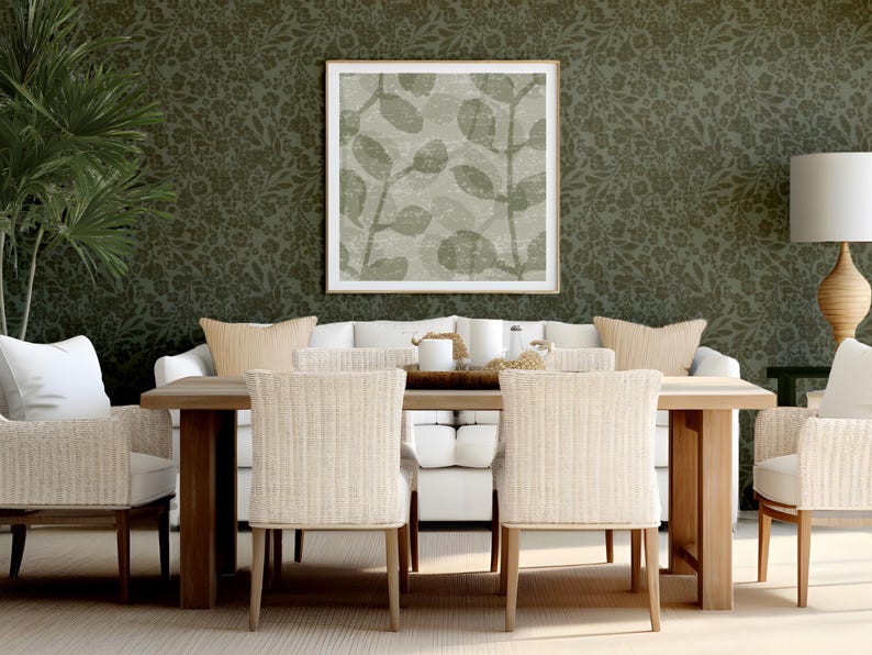 Chic dining room with a wooden table, six wicker chairs, and a white sofa. A large leaf-patterned artwork and green floral wallpaper enhance elegance.
