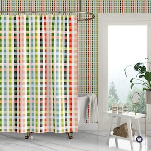 May include: A shower curtain featuring a vertical plaid pattern with alternating stripes in shades of red, orange, yellow, green, blue, and white. The curtain hangs from a metal rod and is suspended by rings, covering a white bathtub in a bathroom.