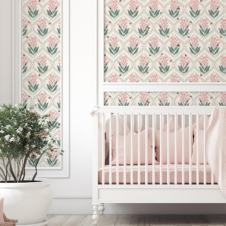 Pode incluir: Um ber&ccedil;o branco com roupa de cama rosa e um cobertor rosa macio. A parede atr&aacute;s do ber&ccedil;o apresenta um design de papel de parede floral com flores rosa, folhas verdes e pequenos detalhes em marrom. Uma planta em vaso est&aacute; &agrave; esquerda.