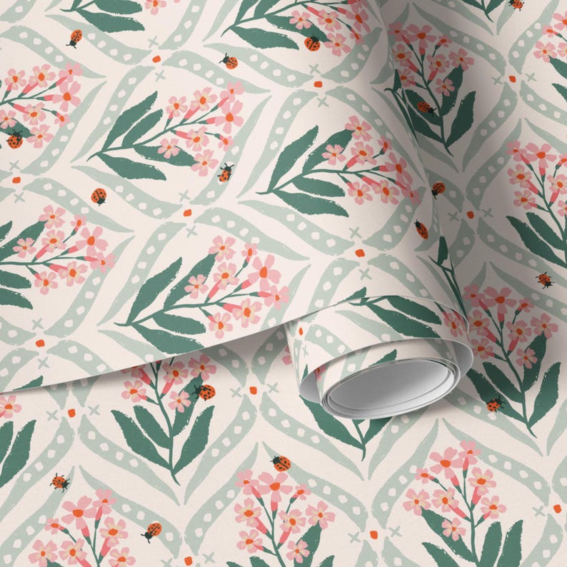 Pode incluir: Papel de parede floral com um padr&atilde;o repetitivo de flores rosa, folhas verdes e joaninhas sobre um fundo creme. O design inclui linhas curvas verde claro com pontos brancos e pequenos detalhes em laranja. Um rolo de papel de parede &eacute; vis&iacute;vel.