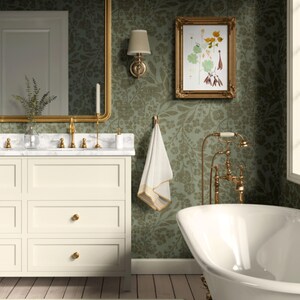 May include: A bathroom featuring a white bathtub, vanity, and framed artwork. The walls are adorned with green floral wallpaper. The vanity has a marble countertop and gold fixtures. A gold-framed mirror hangs above the vanity. A white towel hangs on a gold hook.