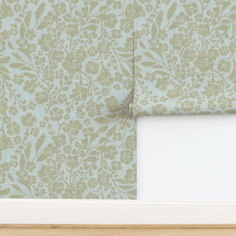 K&ouml;nnte beinhalten: Ein hellblauer Hintergrund mit einem sich wiederholenden Muster aus beigen floralen Zweigen und Bl&auml;ttern.