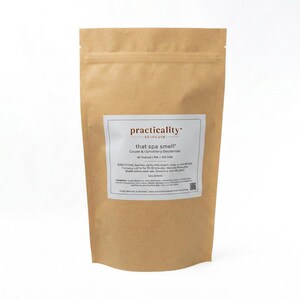 Op de afbeelding: Een bruine papieren zak met tapijt- en bekledingsverfrisser met een wit etiket. Op het etiket staat practicality skincare, that spa smell, Carpet & Upholstery Deodorizer, 12oz (340g) en de gebruiksaanwijzing vermeld.