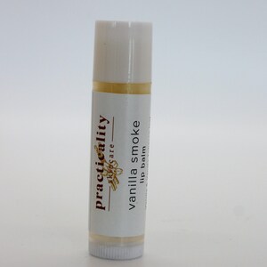 Puede incluir: Un tubo blanco de bálsamo labial de vainilla ahumado con el texto "practicality skincare" y "vanilla smoke lip balm" en la etiqueta.