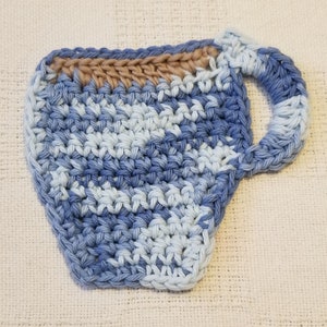 May include: A crocheted blue and white cup coaster with a brown rim. The coaster is shaped like a cup with a handle.