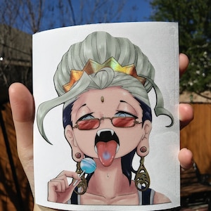 May include: A sticker featuring an anime-style character with gray hair, red-tinted glasses, and fangs. The character has a blue tongue sticking out and is holding a blue lollipop. The character is wearing ornate earrings and a crown.