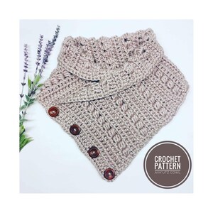 May include: A crocheted cowl in a light brown colour with a button fastening. The cowl is made with a textured stitch pattern and has a wide, folded collar. The text "CROCHET PATTERN AVA'UTZ COWL" is visible in a circle on the right side of the image.