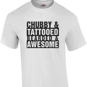 Puede incluir: Camiseta blanca con el texto negro "CHUBBY & TATTOOED BEARDED & AWESOME". La camiseta de cuello redondo tiene mangas cortas. El logotipo de Gildan es visible en la parte superior de la espalda.