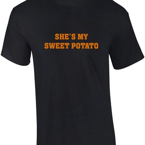 May include: Black t-shirt with orange text that reads "She's my sweet potato".