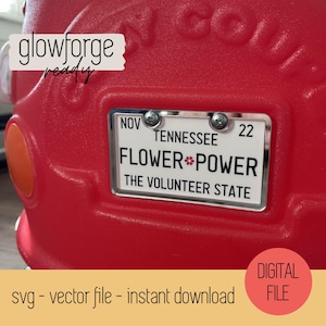 May include: A red plastic toy car with a silver license plate that reads "NOV TENNESSEE 22 FLOWER POWER THE VOLUNTEER STATE". The license plate is a digital download file for a glowforge.