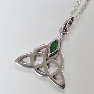 May include: Silver Celtic knot pendant necklace with a green gemstone in the center.