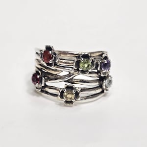 May include: A sterling silver ring featuring a multi-strand band design with an oxidized finish. The ring is adorned with several small, round, multi-colored gemstones, including red, green, purple, and light blue stones set in flower-shaped settings.