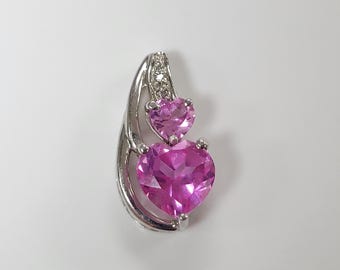 Peut inclure: Un pendentif en argent avec deux pierres précieuses en forme de cœur rose. Le pendentif a un design délicat avec une petite pierre précieuse en forme de cœur au-dessus d'une plus grande pierre précieuse en forme de cœur.