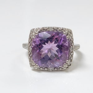 Könnte beinhalten: Ein silberner Ring mit einem großen, quadratischen Amethyst-Edelstein, der von einem Heiligenschein aus kleineren Diamanten umgeben ist.