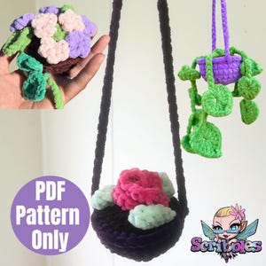 May include: Crocheted hanging plant baskets in purple, black, and green, with pink and white flowers. One basket is suspended by a dark purple cord. The image includes the text "PDF Pattern Only" in a purple circle and a cartoon logo.