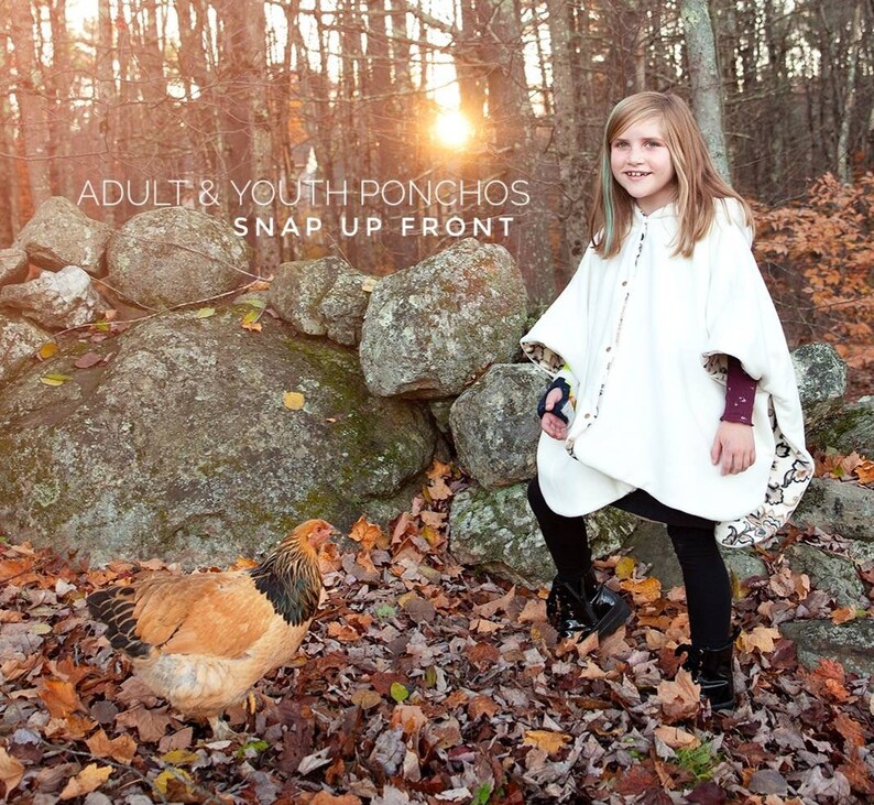 Op de afbeelding: Een witte poncho met een drukknoopsluiting, gedragen door een persoon. De poncho heeft een patroonrand en een capuchon. De afbeelding toont ook een kip en de tekst "ADULT & YOUTH PONCHOS SNAP UP FRONT". De achtergrond omvat een stenen muur en herfstbladeren.
