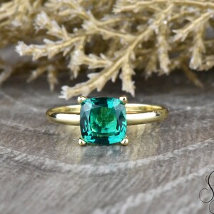 Op de afbeelding: Een gouden ring met een vierkante smaragdgroene edelsteen.