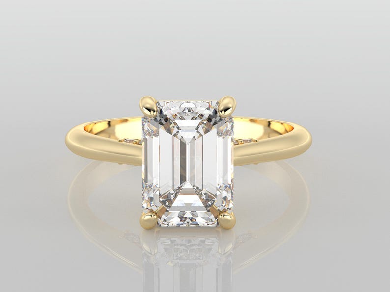 May include: A gold ring with an emerald cut diamond.