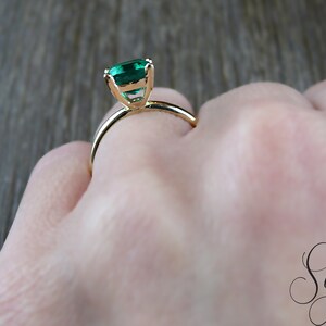 Op de afbeelding: Een gouden ring met een groene edelsteen in een kraalbezetting.
