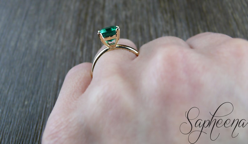 Op de afbeelding: Een gouden ring met een groene edelsteen in een kraalbezetting.