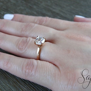May include: A rose gold ring with a large, clear, square-shaped gemstone.