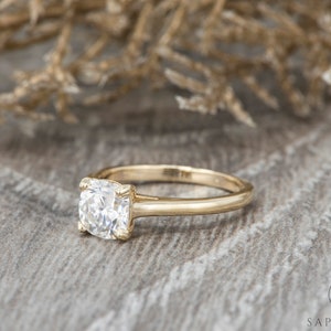 May include: A gold engagement ring with a cushion-cut diamond.