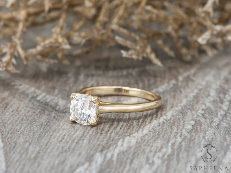 May include: A gold engagement ring with a cushion-cut diamond.