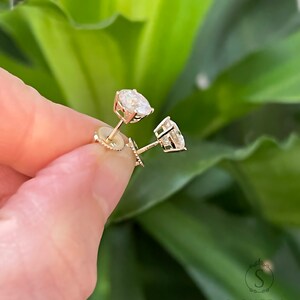 May include: A pair of gold stud earrings with round, clear gemstones.