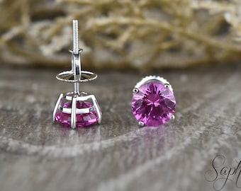 May include: A pair of silver stud earrings with pink gemstones. The earrings have a screw-back closure.