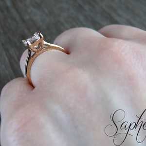 May include: A rose gold engagement ring with a square-shaped diamond.