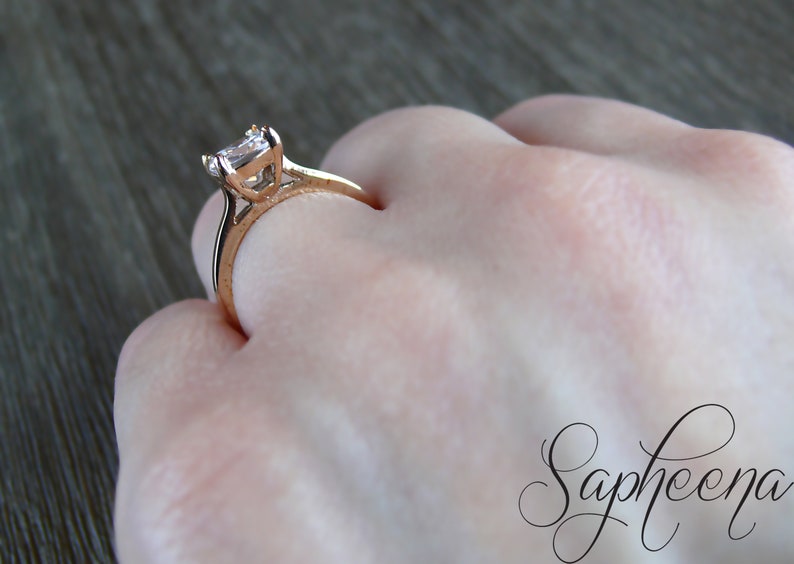 May include: A rose gold engagement ring with a square-shaped diamond.