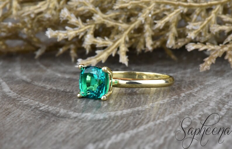 Op de afbeelding: Een gouden ring met een vierkante smaragdgroene edelsteen.