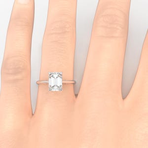 May include: A silver ring with a large, clear emerald-cut diamond.