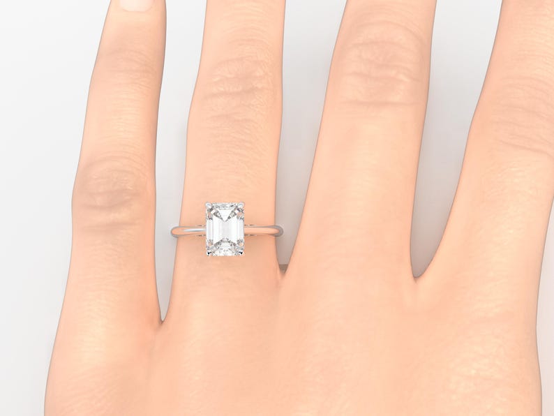 May include: A silver ring with a large, clear emerald-cut diamond.
