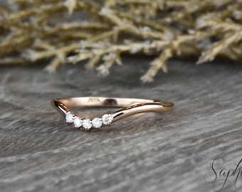 May include: A rose gold wedding band with a curved design and five small diamonds set in a row.