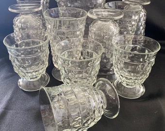 May include: A clear glass drinkware set featuring a pitcher and several glasses. The glasses and pitcher have a textured, geometric pattern. The set includes various sizes of glasses, some with stems, and a pitcher with a handle.
