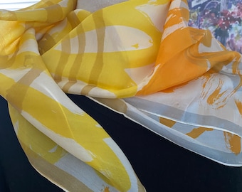 Peut inclure: Un foulard en soie jaune et orange avec un motif abstrait blanc et or. Le foulard a un petit motif d'insecte et le mot "Viva" dans le coin inférieur.