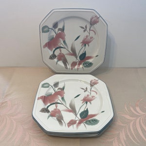 Peut inclure: Ensemble d'assiettes blanches octogonales avec un motif floral de roses roses et de feuilles vertes. Les assiettes ont une bordure bleu fonc&eacute;. Les assiettes sont empil&eacute;es.
