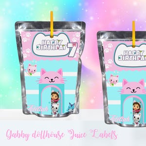 May include: Two juice pouches with a pink and blue Gabby's Dollhouse design. Each pouch features a cat face, the text "Happy Birthday 7", and the name "Adeliah". A yellow straw is attached to the top of each pouch.