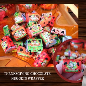 May include: A bowl filled with small chocolate nuggets wrapped in colorful foil featuring Mickey Mouse and friends. The wrappers have a Thanksgiving theme with fall colors and the text "Happy Thanksgiving".