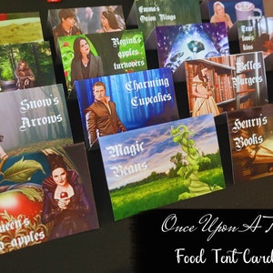 Peut inclure: Un ensemble de cartes de table de nourriture colorées mettant en scène des personnages et des thèmes de la série télévisée Once Upon A Time. Les cartes présentent des images de personnages comme Regina, Blanche-Neige et Rumplestiltskin, ainsi que du texte décrivant divers articles alimentaires, tels que "Regina's apples, turnovers", "Snow's Arrows", et "Rumple's". Les cartes sont conçues pour être utilisées lors d'une fête ou d'un événement pour identifier différents articles alimentaires.