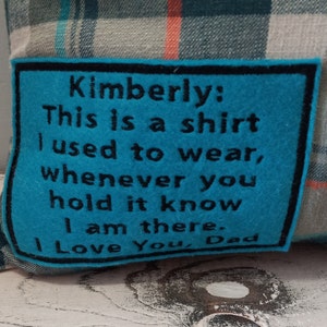 May include: Plaid cushion with a teal felt patch. The patch has black text that reads, "Kimberly: This is a shirt I used to wear, whenever you hold it know I am there. I Love You, Dad."
