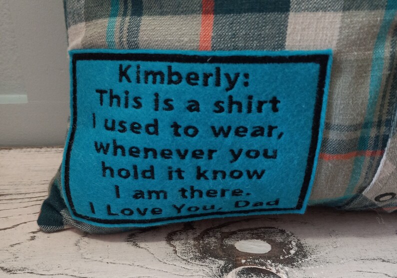 May include: Plaid cushion with a teal felt patch. The patch has black text that reads, "Kimberly: This is a shirt I used to wear, whenever you hold it know I am there. I Love You, Dad."
