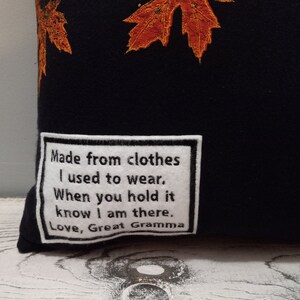 May include: Black pillow with embroidered orange and yellow fall leaves. A white patch with black text reads: "Made from clothes I used to wear. When you hold it know I am there. Love, Great Gramma."