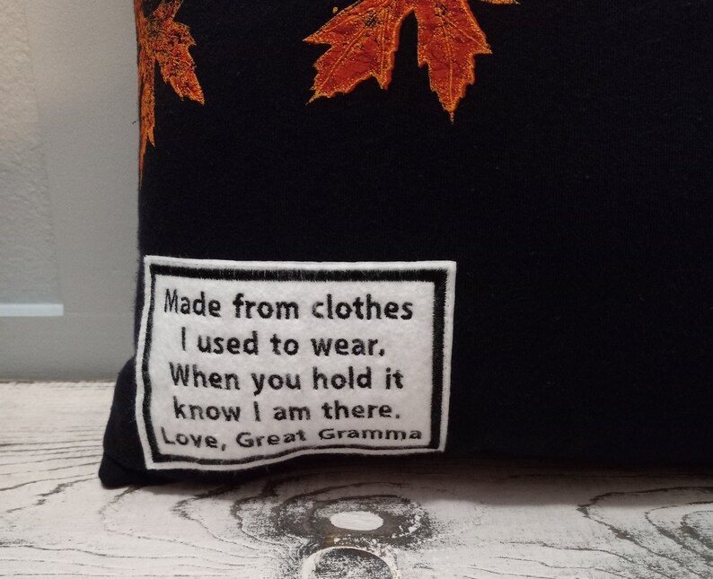 May include: Black pillow with embroidered orange and yellow fall leaves. A white patch with black text reads: "Made from clothes I used to wear. When you hold it know I am there. Love, Great Gramma."