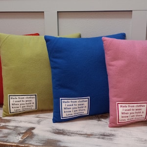 May include: Four square throw pillows in red, green, blue, and pink. Each pillow has a white label with black text that reads "Made from clothes I used to wear. When you hold it know I am there. Love, Great Gramma/Gramma".