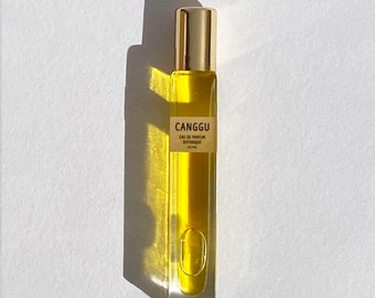 Pode incluir: Um pequeno frasco de vidro transparente com uma tampa dourada e um líquido amarelo dentro. O frasco é etiquetado com "CANGGU EAU DE PARFUM BOTANIQUE 10ml/0.33fl.oz."