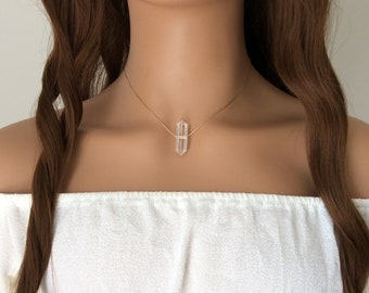 May include: A gold chain necklace with a clear quartz crystal pendant. The crystal is faceted and has a geometric shape.
