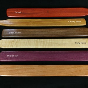 May include: Six wooden paddles in different wood types, including Padauk, Canary Wood, Black Walnut, Curly Maple, Purpleheart, and Cherry.