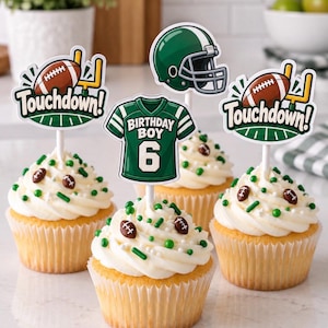 Puede incluir: Cuatro cupcakes con glaseado blanco y chispas temáticas de fútbol americano, cada uno con un adorno de papel. Los adornos muestran un balón marrón con postes amarillos y el texto Touchdown, un casco verde y una camiseta verde con Birthday Boy 6.